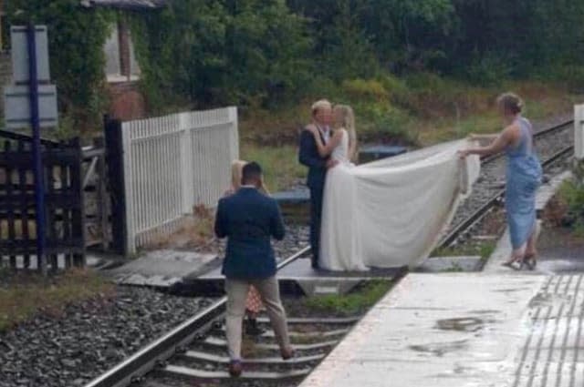 Bride in white dress pictured with groom trespassing on railway line for express wedding