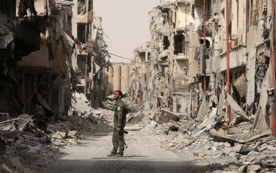 A fighter from the Syrian Democratic Forces (SDF) stands next to debris of damaged buildings in Raqqa, Syria, on Sept. 25, 2017. (Photo: Rodi Said / Reuters)