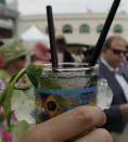 FILE - In this May 3, 2013, file photo, a spectator holds a mint julep before the running of the 139th Kentucky Oaks at Churchill Downs in Louisville, Ky. There will be no Run for the Roses on this first Saturday in May. The Kentucky Derby is one of the events that won't be held this week because of the coronavirus pandemic. (AP Photo/Charlie Riedel, File)