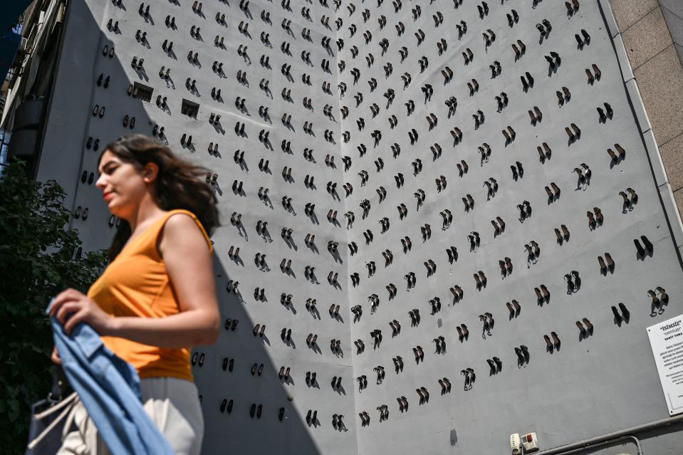 A woman passes in front of a contemporary art installation by Turkish artist Vahit Tuna in an attempt to raise awareness on women killed by domestic violence by their partners and husbands, on September 17, 2019 in Istanbul. - Turkish artist Vahiot Tuna placed 440 pair of female shoes on the walls of a building to symbolize women killed by their partners and husbands in 2018 in Turkey. (Photo by Ozan KOSE / AFP) / RESTRICTED TO EDITORIAL USE - MANDATORY MENTION OF THE ARTIST UPON PUBLICATION - TO ILLUSTRATE THE EVENT AS SPECIFIED IN THE CAPTION        (Photo credit should read OZAN KOSE/AFP/Getty Images)