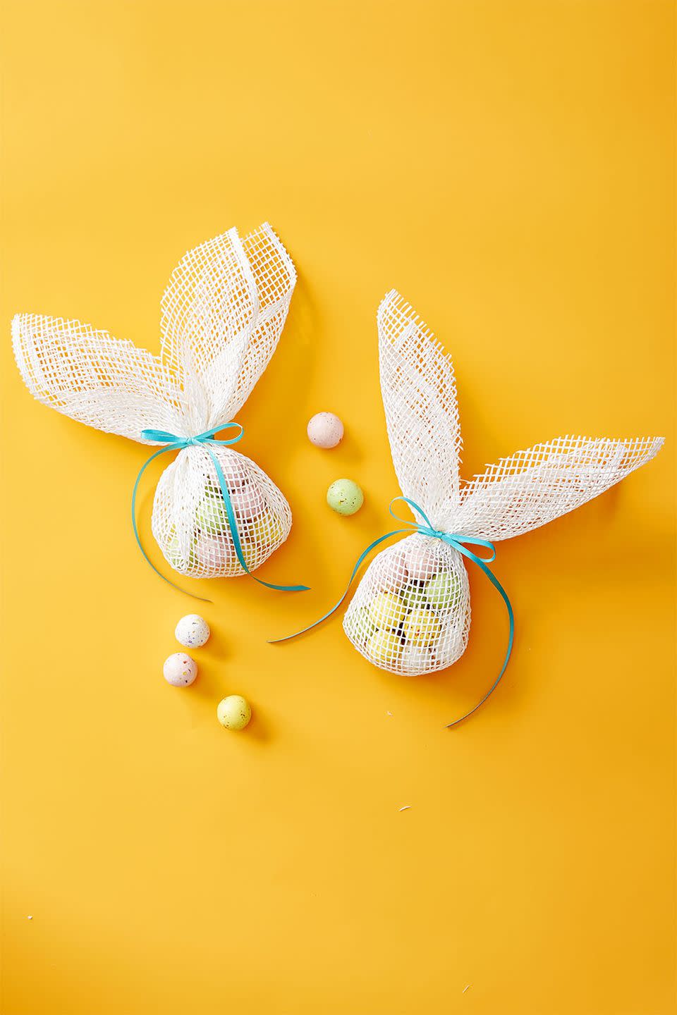 <p>Place candy in the middle of a 10" x 20" piece of burlap fabric. Fold sides then tie fabric at the top with a ribbon. Cut a "V" shape from the center of the excess fabric to create bunny ears.</p>