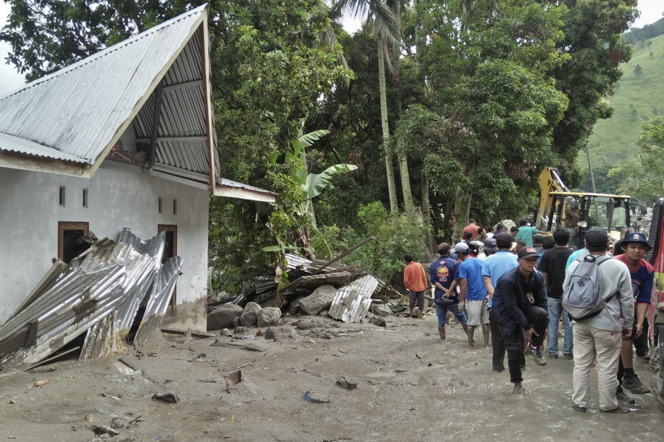 Rescue workers and residents inspect the damage caused by a landslide in Simangulampe village, North Sumatra, Indonesia, Saturday, Dec. 2, 2023. Torrential rain triggered flash floods and a landslide on Indonesia's Sumatra island, leaving a number of people missing, officials said Saturday. (AP Photo/Hermanto Tobing)