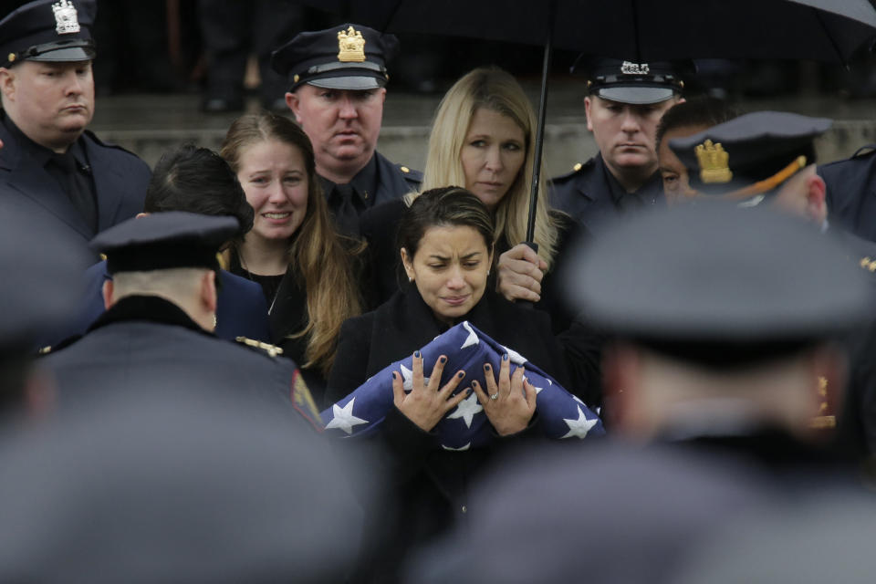 The wife of Jersey City Police Detective Joseph Seals, Laura Seals, center, receives an American flag during his funeral in Jersey City, N.J., Tuesday, Dec. 17, 2019. The 40-year-old married father of five was killed in a confrontation a week ago with two attackers who then drove to a kosher market and killed three people inside before dying in a lengthy shootout with police. (AP Photo/Seth Wenig)