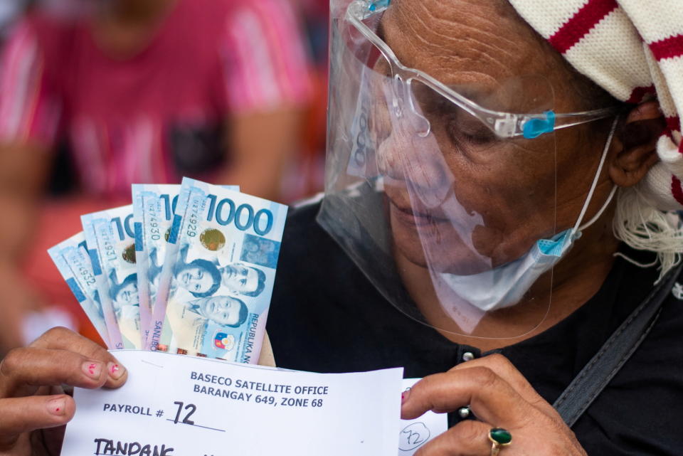 A woman receives cash assistance from the government following the imposition of two-week lockdown to prevent the spread of the coronavirus Delta variant, at an elementary school in Manila, Philippines, August 11, 2021. REUTERS/Lisa Marie David     TPX IMAGES OF THE DAY