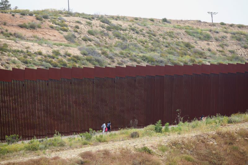 Migrants reach the border to request asylum to U.S. authorities between the two border fences, in Tijuana