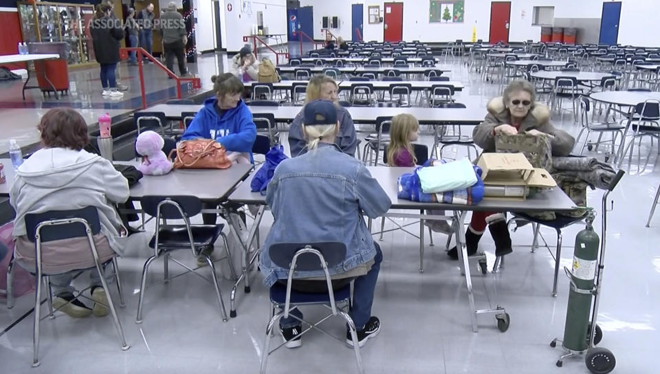 This image taken from video and provided by WTVQ shows people sitting at a table at Rockcastle Middle School being used as an evacuation center in Mt Vernon, Ky., Wednesday, Nov. 22, 2023. People were evacuated from a nearby town after a CSX train derailed Wednesday near Livingston, a remote town with about 200 people in Rockcastle County. CSX says two of the 16 cars that derailed carried molten sulfur, which caught fire after the cars were breached. (WTVQ via AP)