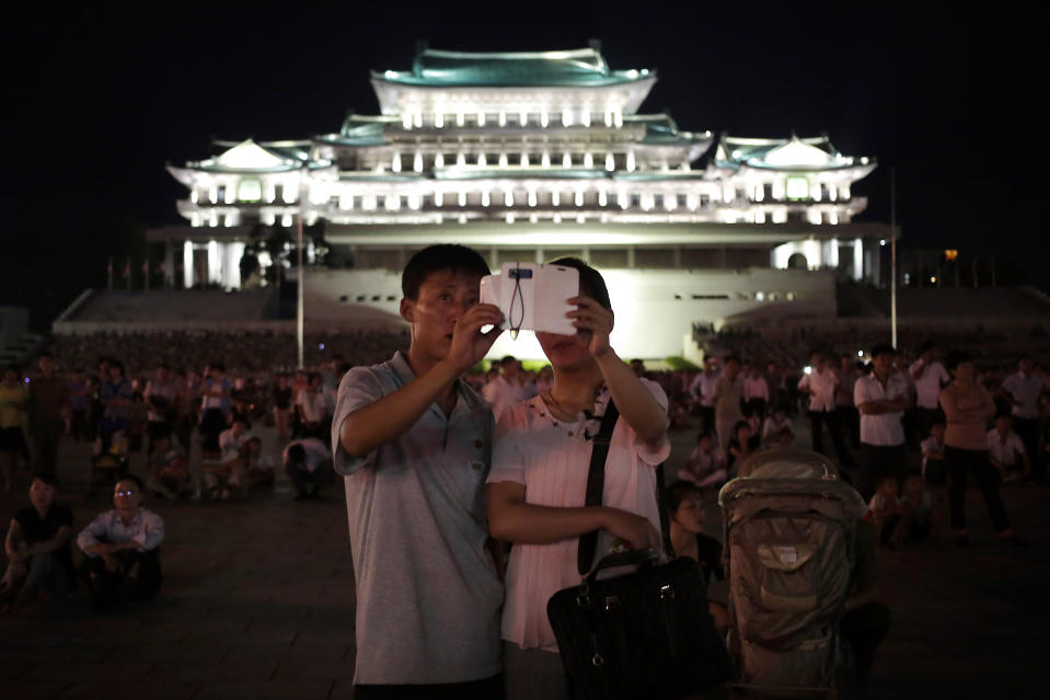 A North Korean couple use their smart phone to photograph fireworks, Sunday, July 27, 2014 in central Pyongyang, North Korea. North Koreans gathered at Kim Il Sung Square to watch a fireworks display as part of celebrations for the 61st anniversary of the armistice that ended the Korean War.(AP Photo/Wong Maye-E)