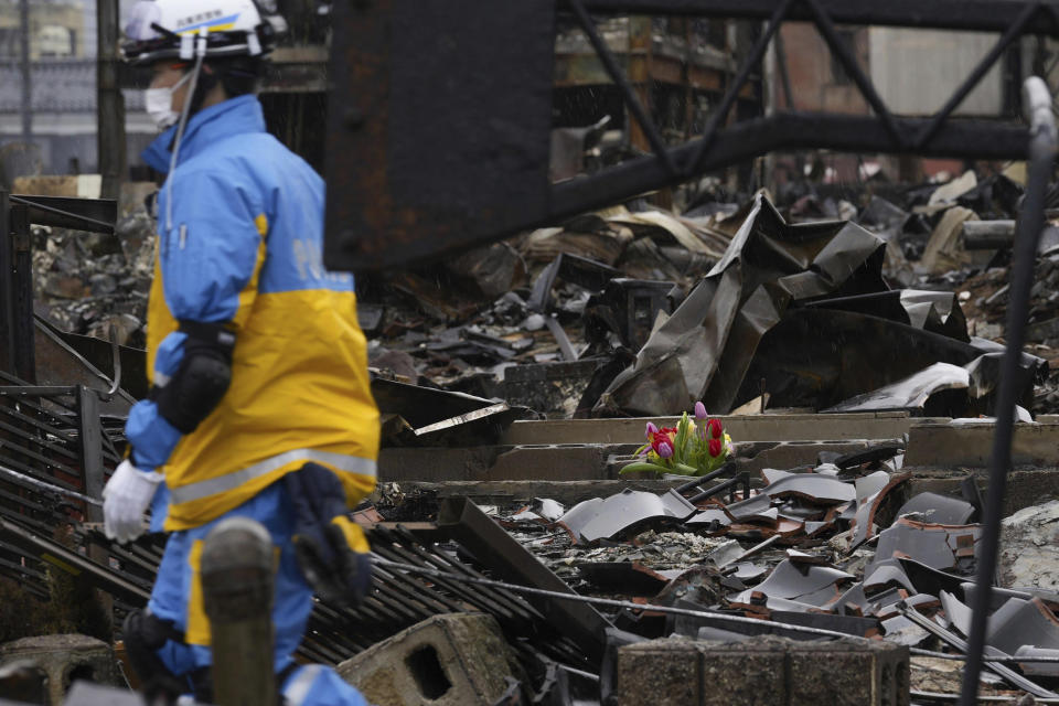 Tulips are offered at a burnt-out house in Wajima, Ishikawa prefecture, Japan Sunday, Jan. 7, 2024. A major earthquake slammed western Japan on Jan. 1, killing scores of people, toppling buildings and setting off landslides. (Kyodo News via AP)