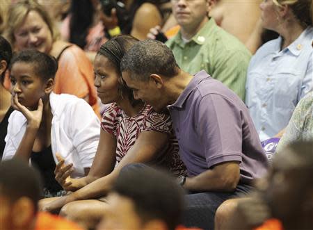 U.S President Barack Obama hugs first lady Michelle as they watch the Diamond Head basketball game between Oregon State and Akron during their Christmas vacation in Honolulu, Hawaii, December 22, 2013. REUTERS/Hugh Gentry