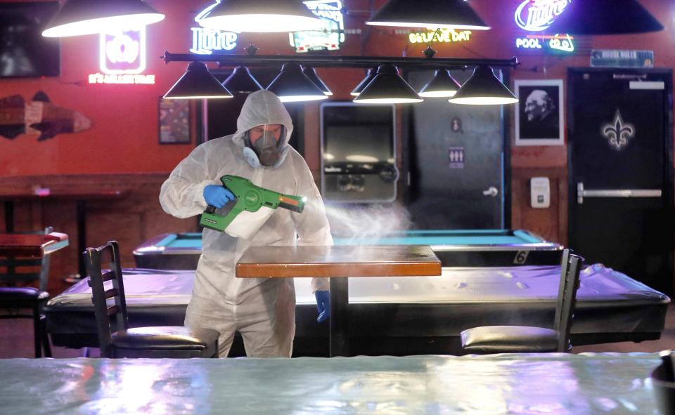 FILE - In this May 22, 2020, file photo, Tyler Page, a technician with 6 & Fix, Inc., help disinfect and protect Sharky's Place in Raleigh, N.C. Coronavirus cases are rising in nearly half the U.S. states, as states are rolling back lockdowns. (Robert Willett/The News & Observer via AP)