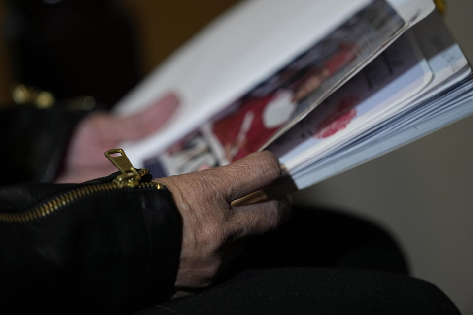 Irma Reyes looks through a scrapbook as she sits on her daughter's bed with dogs Stacy and Georgie, Wednesday, Feb. 1, 2023. Reyes' daughter was one of two teens who men were accused of keeping at a San Antonio motel where other men paid to have sex with them in 2017. Their cases have seen years of delay, a parade of prosecutors, an aborted trial and, ultimately, a stark retreat by the government with the offer of a plea deal. (AP Photo/Eric Gay)