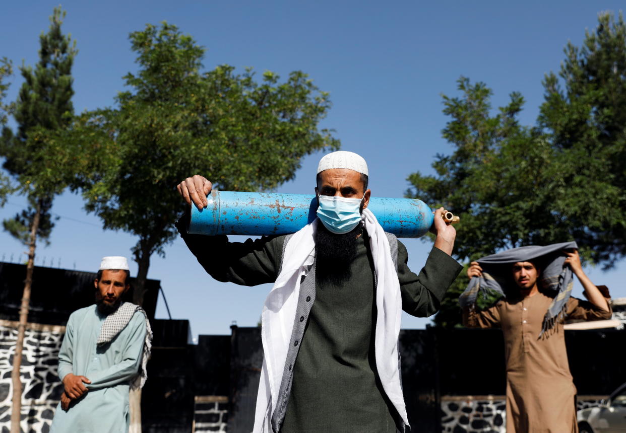 A man waits outside a factory to get his oxygen cylinder refilled as he holds it on his shoulder, amidst the spread of the coronavirus disease (COVID-19) in Kabul, Afghanistan June 15, 2021. REUTERS/Stringer