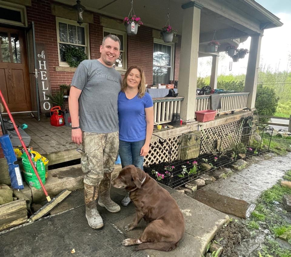 Jamey and Brandy Godin stand in front of their Stoystown home with their dog, Truffles.