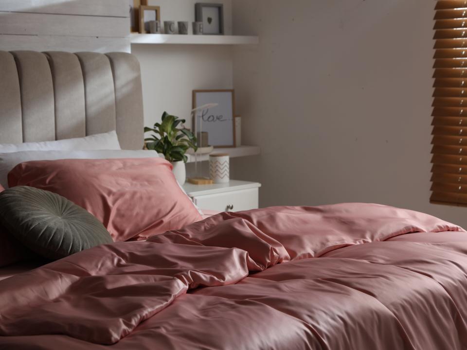 Silky pink duvet on bed in white room