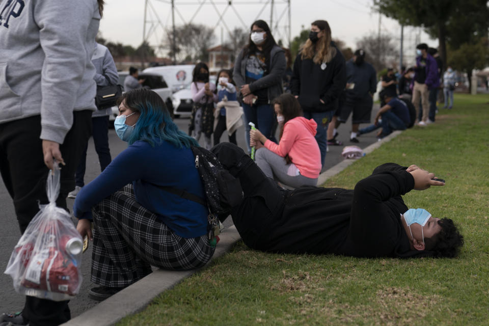 FILE — Robert Rodriguez, 14, looks at his phone while waiting in line for a test at a mobile COVID-19 testing site in Paramount, Calif., Wednesday, Jan. 12, 2022. California is showing signs that it may have turned the corner on the latest omicron wave of the corona virus pandemic with cases falling and hospitalizations short of the overwhelming deluge that officials had predicted earlier. (AP Photo/Jae C. Hong, File)