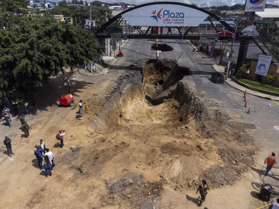 Se trabaja en un sumidero en la carretera principal de Villa Nueva, Guatemala, el martes 27 de septiembre de 2022. Se estaban realizando esfuerzos de búsqueda de una madre y su hija que desaparecieron cuando su vehículo cayó a un enorme pozo al desmoronarse una calle. (Foto AP/Moisés Castillo)