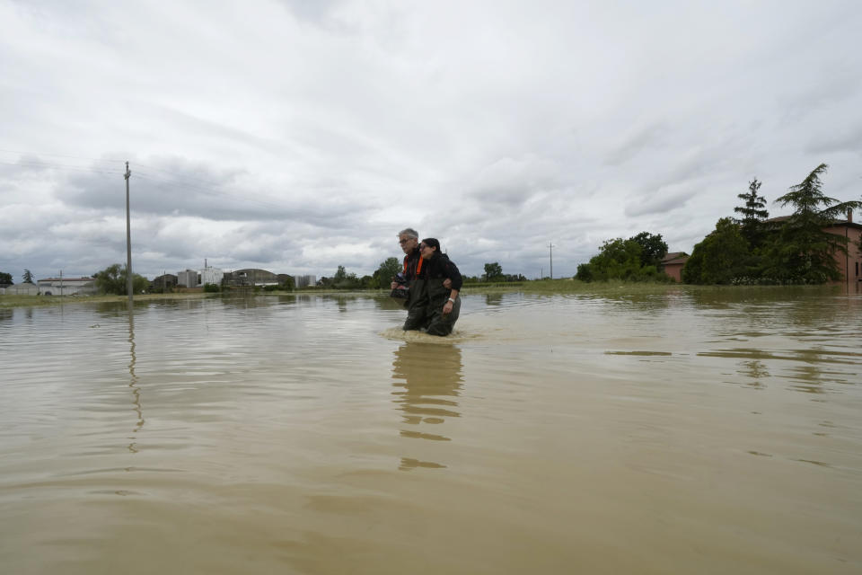 A couple walk in a flooded road of Lugo, Italy, Thursday, May 18, 2023. Exceptional rains Wednesday in a drought-struck region of northern Italy swelled rivers over their banks, killing at least eight people, forcing the evacuation of thousands and prompting officials to warn that Italy needs a national plan to combat climate change-induced flooding. (AP Photo/Luca Bruno)