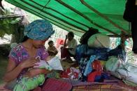 Woman displaced by fighting in eastern Myanmar feeds a baby at a forest camp in Kayah State