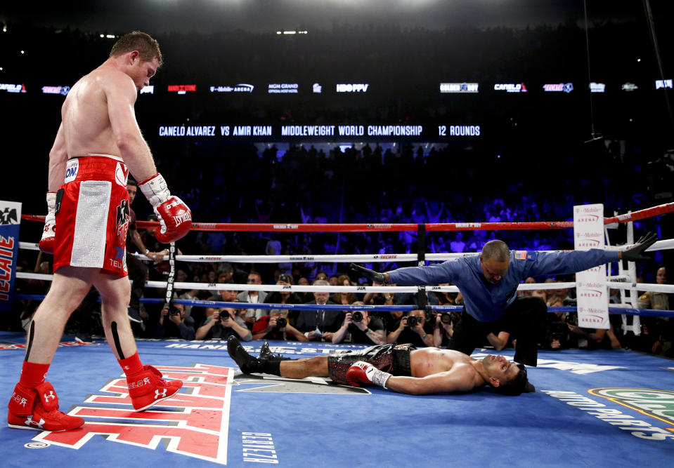 2016 AP YEAR END PHOTOS - Canelo Alvarez, left, watches after knocking down Amir Khan during their WBC middleweight title fight on May 7, 2016, in Las Vegas. (AP Photo/John Locher, File)