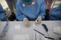 Un trabajador de la salud realiza pruebas rápidas de coronavirus en el mercado de alimentos de Coche en Caracas, Venezuela, el martes 23 de junio de 2020. (AP Foto/Ariana Cubillos)