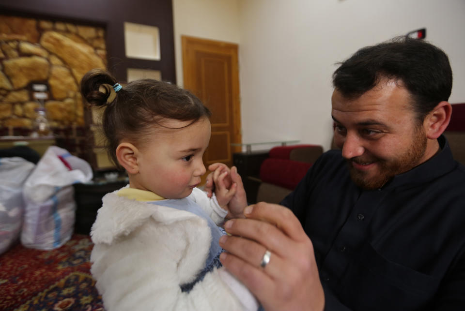 In this Sunday, Feb. 23, 2020 photo, Abdullah Mohammed plays with his daughter, three-year-old Salwa inside a house he recently fled to, near the Syrian-Turkish border, in Sarmada, Syria. Mohammed would do anything for his daughter, even if that means forcing himself to laugh with her at the sound of exploding bombs, to help her overcome her fear. Mohammed and Salwa became an overnight celebrity after a video they shot spread on social media, widely shared as a reminder of the horrors faced by children in Syria. (AP Photo/Ghaith Alsayed)