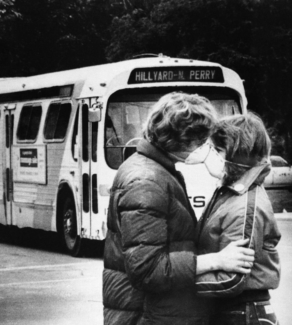 Fifteen-year-old Heidi Havens gives Allen Troup, 16, a kiss as he prepares to board a Spokane City bus, May 27, 1980. Spokane residents have had to wear face masks while outside for nine days now because of possible health threats from volcanic ash sprayed over the area by Mount St. Helens on May 18. Having had them on for so long, some people are obviously forgetting.