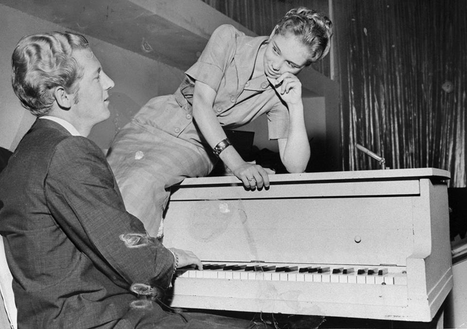 Jerry Lee Lewis playing piano with Myra Gale Brown sitting on it