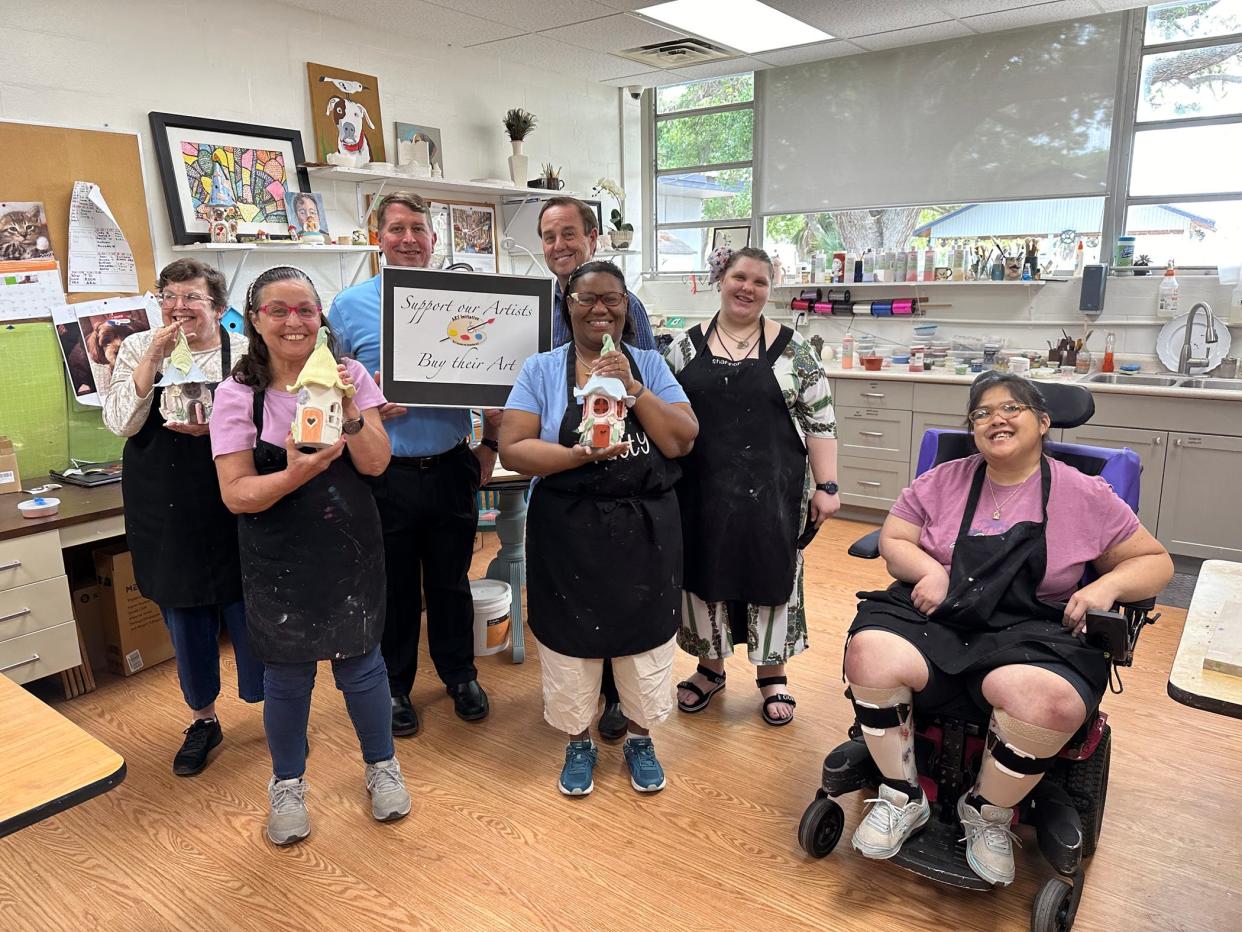 Coming together on World Autism Awareness Day were Goodwill Manasota president Donn Githens and Easterseals Southwest Florida president Tom Waters (holding sign) with Art Initiative Program participants, from left, Denise, Ana, Patty, Shannon and Julie.