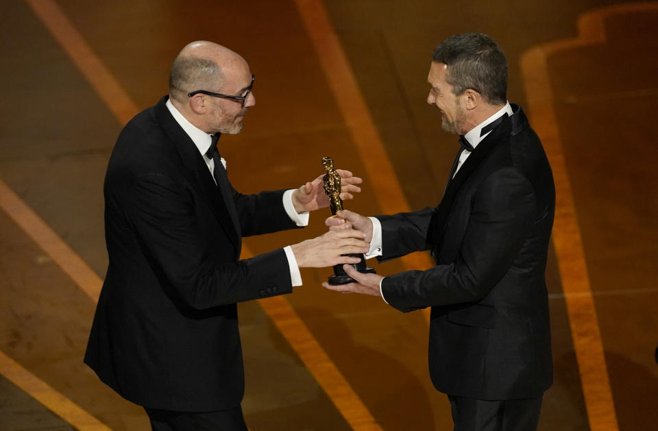 Antonio Banderas, right, presents Edward Berger with the award for "All Quiet on the Western Front" from Germany, for best international feature film at the Oscars on Sunday, March 12, 2023, at the Dolby Theatre in Los Angeles. (AP Photo/Chris Pizzello)