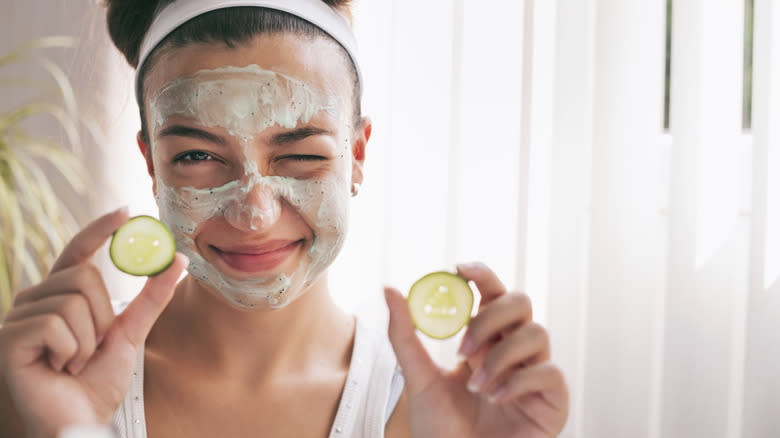 woman lotion mask holds cucumber