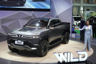 A Thai model poses next to Vinfast's electric concept pickup trucks called "Wild" during the 45th Bangkok Motor Show in Nonthaburi, Thailand, Tuesday, March 26, 2024. (AP Photo/Sakchai Lalit)