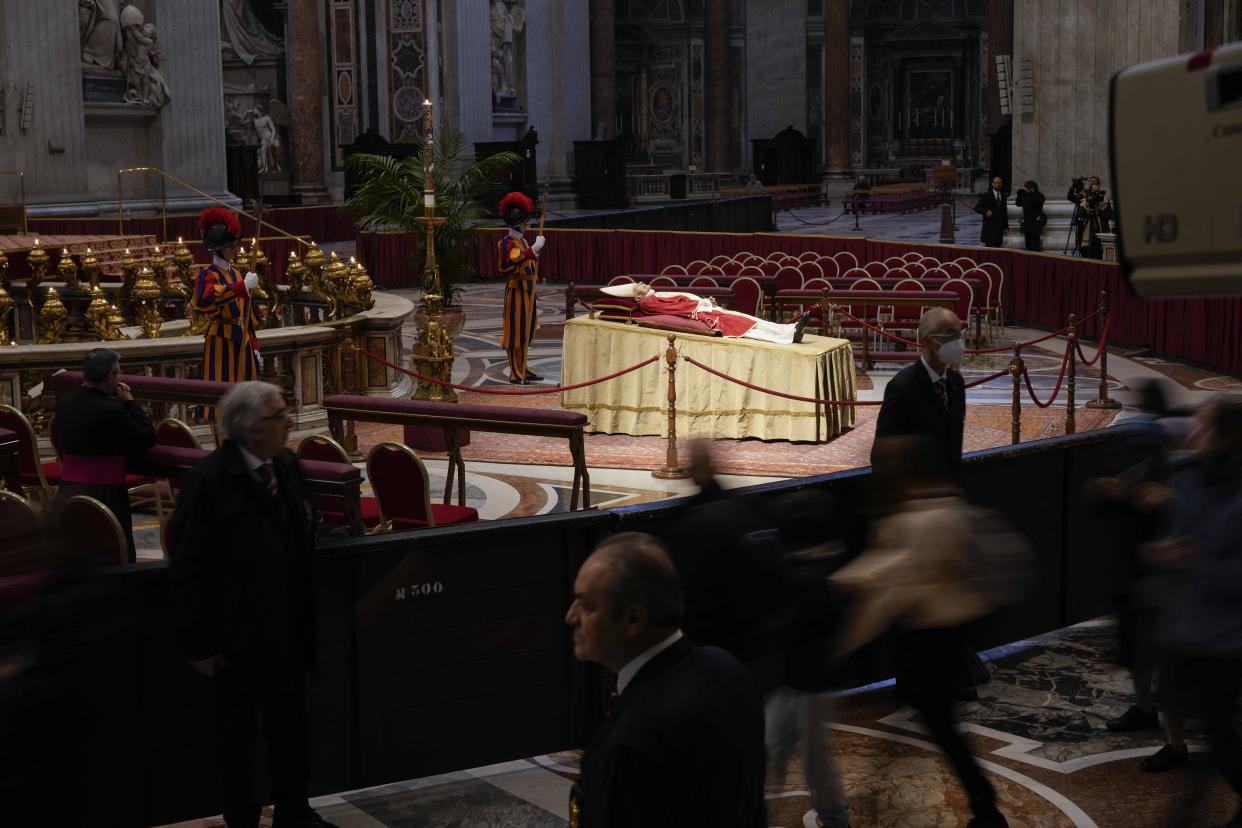 People look at the body of late Pope Emeritus Benedict XVI laid out in state inside St. Peter's Basilica at The Vatican, Monday, Jan. 2, 2023. Benedict XVI, the German theologian who will be remembered as the first pope in 600 years to resign, has died, the Vatican announced Saturday. He was 95. (AP Photo/Andrew Medichini)