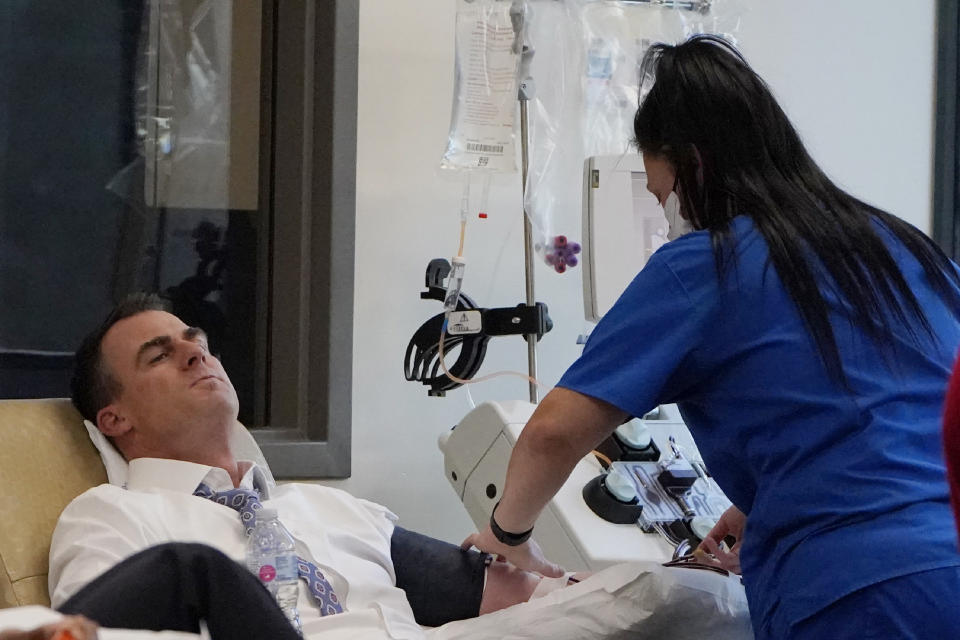 Oklahoma Gov. Kevin Stitt, left, donates convalescent plasma at the Oklahoma Blood Institute in Oklahoma City, Tuesday, Dec. 1, 2020. This is Gov. Stitt's second time donating plasma since he tested positive for the coronavirus in July. (AP Photo/Sue Ogrocki)