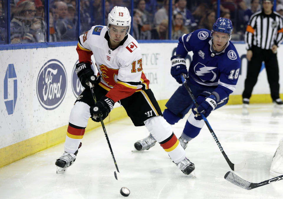 Calgary Flames left wing Johnny Gaudreau (13) carries the puck past Tampa Bay Lightning left wing Ondrej Palat (18) during the third period of an NHL hockey game, Jan. 11, 2018, in Tampa, Fla. Executives around the NHL expect plenty of movement before free agency opens Wednesday, July 13, 2022. Several top players including Gaudreau and Palat could still sign contracts prior to hitting the open market. (AP Photo/Chris O'Meara, file)