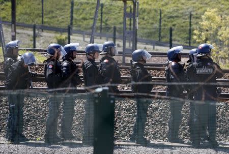 French gendarmes stand near the tracks after workers operating on the MyFerryLink car and passenger ferry boats set tires into fire at the entrance of the Eurotunnel Channel Tunnel linking Britain and France in Coquelles near Calais, northern France, June 30, 2015. REUTERS/Vincent Kessler