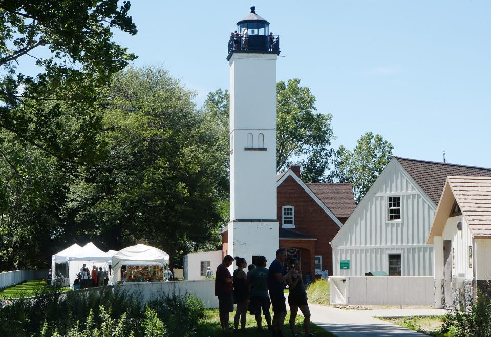 People explore the grounds of the Presque Isle Lighthouse at Presque Isle State Park during Discover Presque Isle.