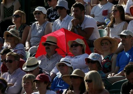 A couple shelter from the sun with a red umbrella at the Wimbledon Tennis Championships in London, June 29, 2015. REUTERS/Stefan Wermuth