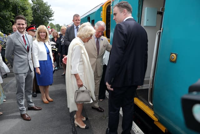 The Prince of Wales helps the Duchess of Cornwall board a train during a visit to Llandovery Railway Station to mark the 150th anniversary of the Heart of Wales railway line. Andrew Matthews/PA Wire