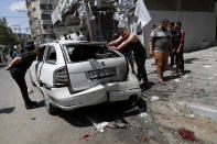Residents inspect a car that was hit in an Israeli airstrike that killed three people in the car, on the main road in Gaza City, Wednesday, May 12, 2021. (AP Photo/Adel Hana)