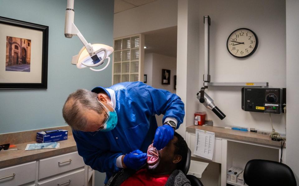 Musician Roland Kemokai has his teeth checked Nov. 19 by Dr. Alan Moore as part of the Capital Area Dental Foundation's donation to Season For Caring recipients.