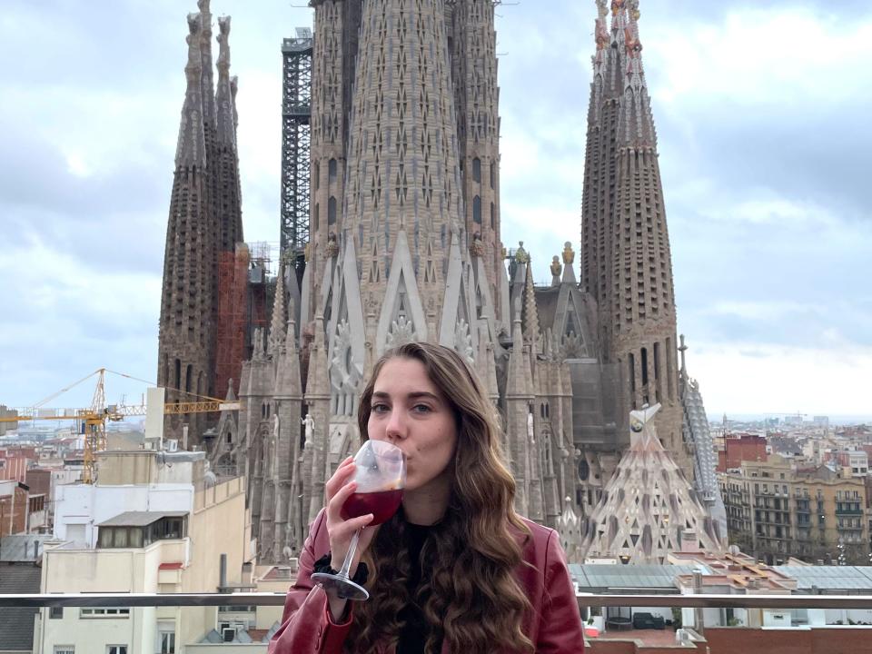 Dasha drinking a glass of red wine on a balcony. Behind her is La Sagrada Familia.