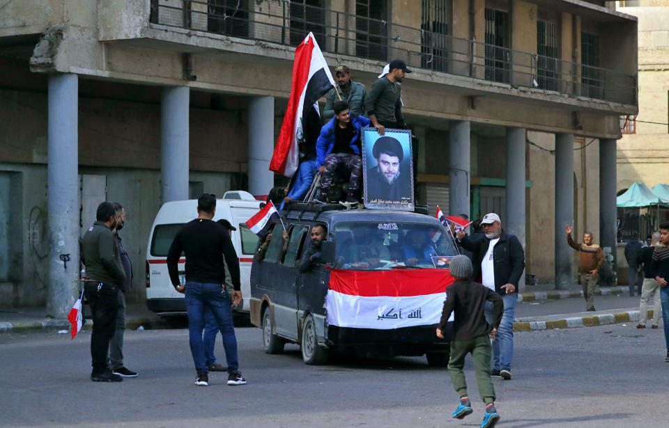 Followers of Shiite cleric Muqtada al-Sadr, in the poster, head to Tahrir Square, Baghdad, Iraq, Friday, Nov. 27, 2020. Thousands took to the streets in Baghdad on Friday in a show of support for a radical Iraqi cleric ahead of elections slated for next year, stirring fears of a spike in coronavirus cases. (AP Photo/Khalid Mohammed)