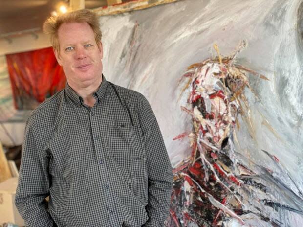 Patrick John Mills stands beside one of his latest paintings. It's part of a series titled Malignant, which Mills started after being diagnosed with chronic lymphocytic leukemia. (Robyn Miller/CBC - image credit)