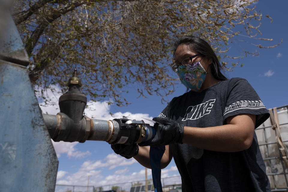 FILE - Raynelle Hoskie attaches a hose to a water pump to fill tanks in her truck outside a tribal office on the Navajo reservation in Tuba City, Ariz., on April 20, 2020. The Supreme Court has ruled against the Navajo Nation in a dispute involving water from the drought-stricken Colorado River. States that draw water from the river — Arizona, Nevada and Colorado — and water districts in California had urged the court to decide for them, and that's what the justices did in a 5-4 ruling. (AP Photo/Carolyn Kaster, File)