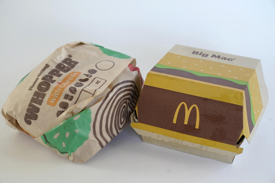 A Burger King Whopper in a wrapper, left, rests next to a McDonald's Big Mac in a container, in Walpole, Mass., Wednesday, April 20, 2022. Environmental and health groups are pushing dozens of fast food companies, supermarket chains and other retail outlets to remove PFAS from their packaging. (AP Photo/Steven Senne)