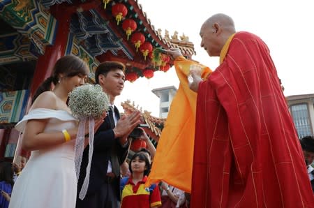 A newly-wed couple is blessed by a priest during a mass weddingÊin Kuala Lumpur