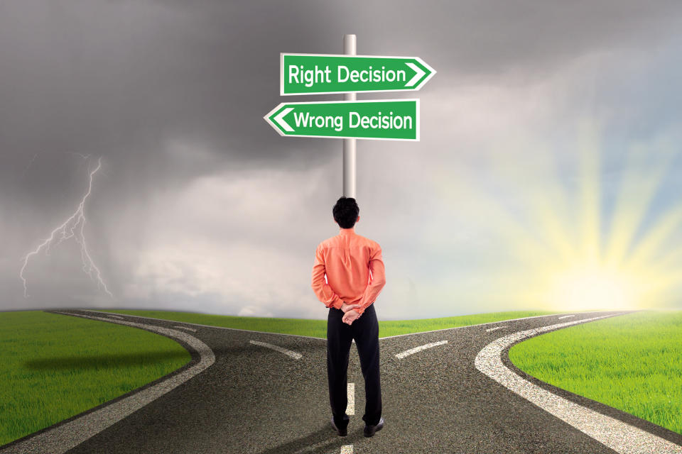 e road with signs reading "Right Decision" and "Wrong Decision"Man standing at a fork in th