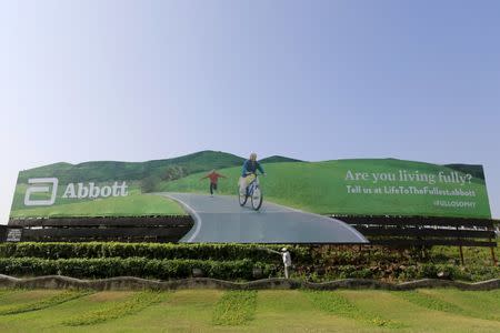 A worker waters plants next to an advertisement billboard of Abbott in Mumbai, India, in this file picture taken November 12, 2015. REUTERS/Danish Siddiqui/Files