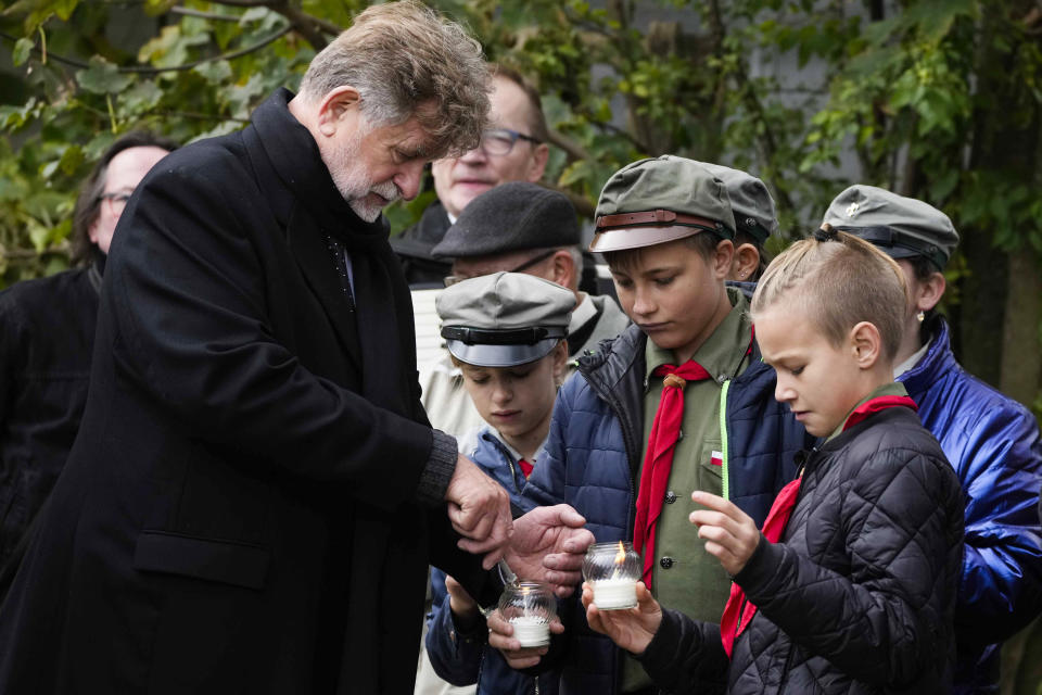 School children gather with the mayor and other members of the town during a ceremony commemorating 60 Jews executed in the town during the Holocaust in Wojslawice, Poland, on Thursday Oct. 14, 2021. It is one of many mass grave sites to be discovered in recent years in Poland, which during World War II was occupied by Adolf Hitler’s forces. (AP Photo/Czarek Sokolowski)