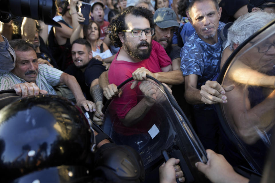 Anti-government protesters scuffle with police outside Congress after a bill promoted by Argentine President Javier Milei was approved in general by the lower house of Congress, in Buenos Aires, Argentina, Friday, Feb. 2, 2024. The bill, that includes a broad range of economic, administrative, criminal and environmental reforms, must now be debated article by article and will then be sent to the Senate. (AP Photo/Natacha Pisarenko)